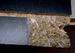 Particle board entertainment center shelf before, closeup.