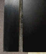 Particle board entertainment center shelf after repairs close up.